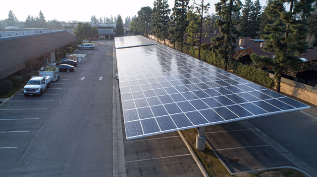 Spacious parking lot featuring a large carport topped with solar panels, built on galvanized steel structures by Coatinc US.