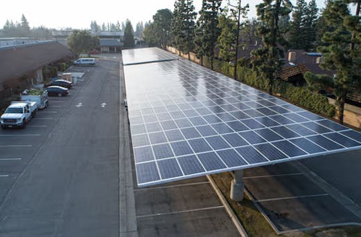 Spacious parking lot featuring a large carport topped with solar panels, built on galvanized steel structures by Coatinc US.