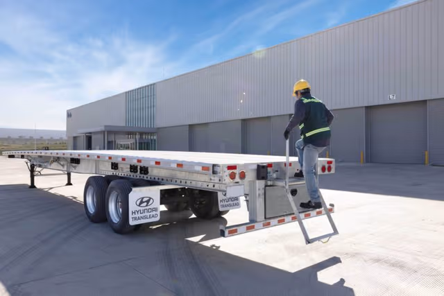Galvanized steel trailer parked in a lot with a worker nearby, showcasing durable trailer galvanizing and reliability by Coatinc US.