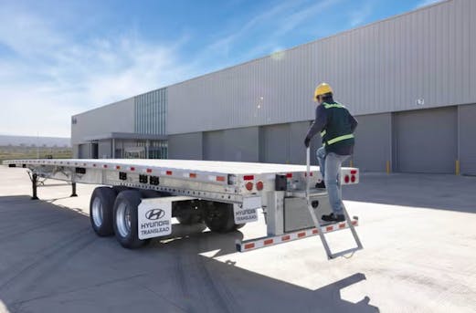 Galvanized steel trailer parked in a lot with a worker nearby, showcasing durable trailer galvanizing and reliability by Coatinc US.