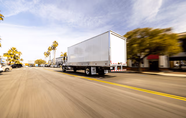 Galvanized steel trailer with mounted structure driving on a local road, showcasing durable corrosion protection through trailer galvanizing by Coatinc US