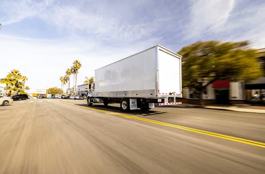 Galvanized steel trailer with mounted structure driving on a local road, showcasing durable corrosion protection through trailer galvanizing by Coatinc US