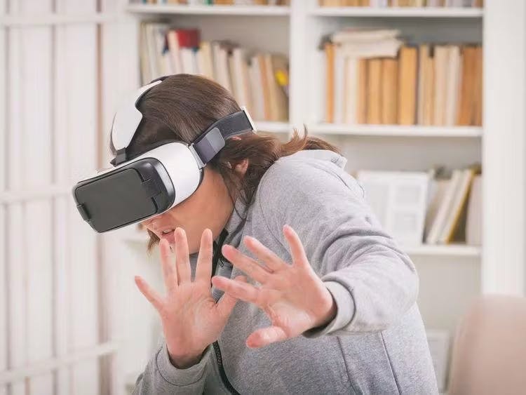 Girl wearing virtual reality mask with hands out in front of her.