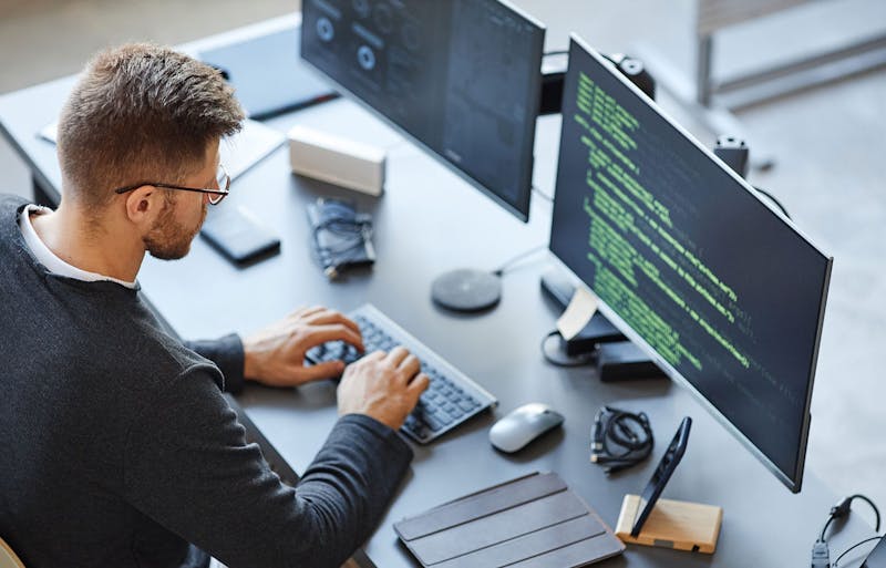 A male software engineer writing code at his workstation