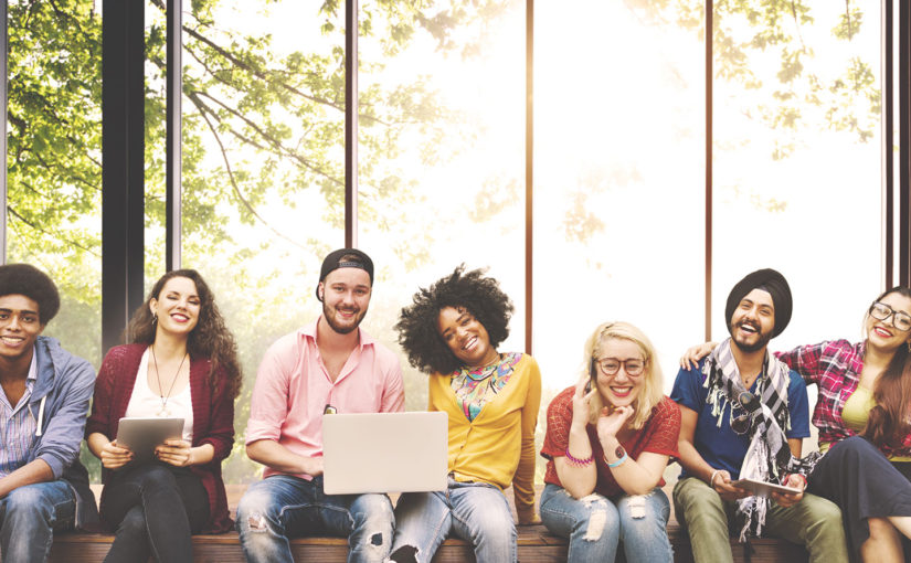 A diverse group of young adults smiling together in a bright, modern setting.