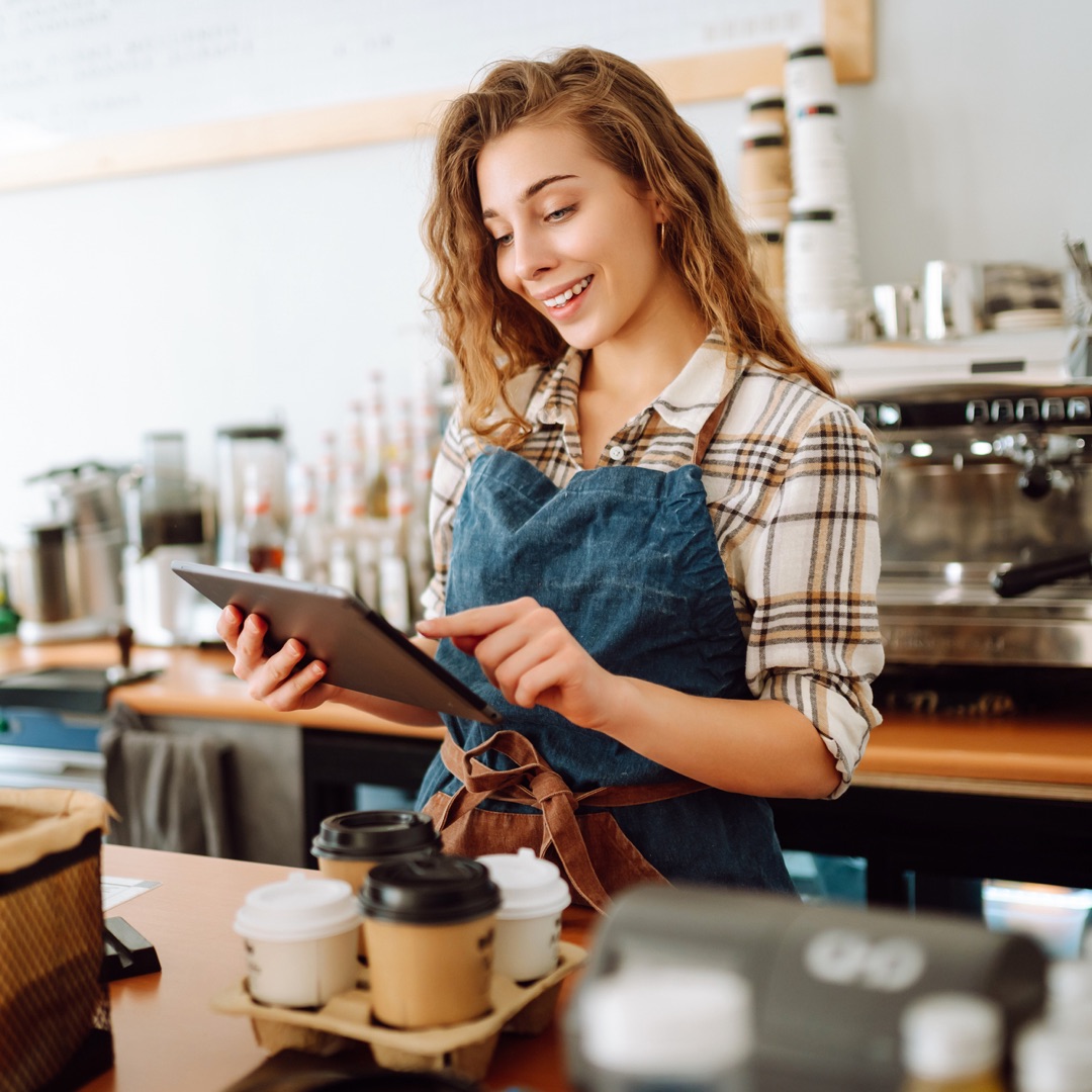 Barista using a tablet in a coffee shop setting.