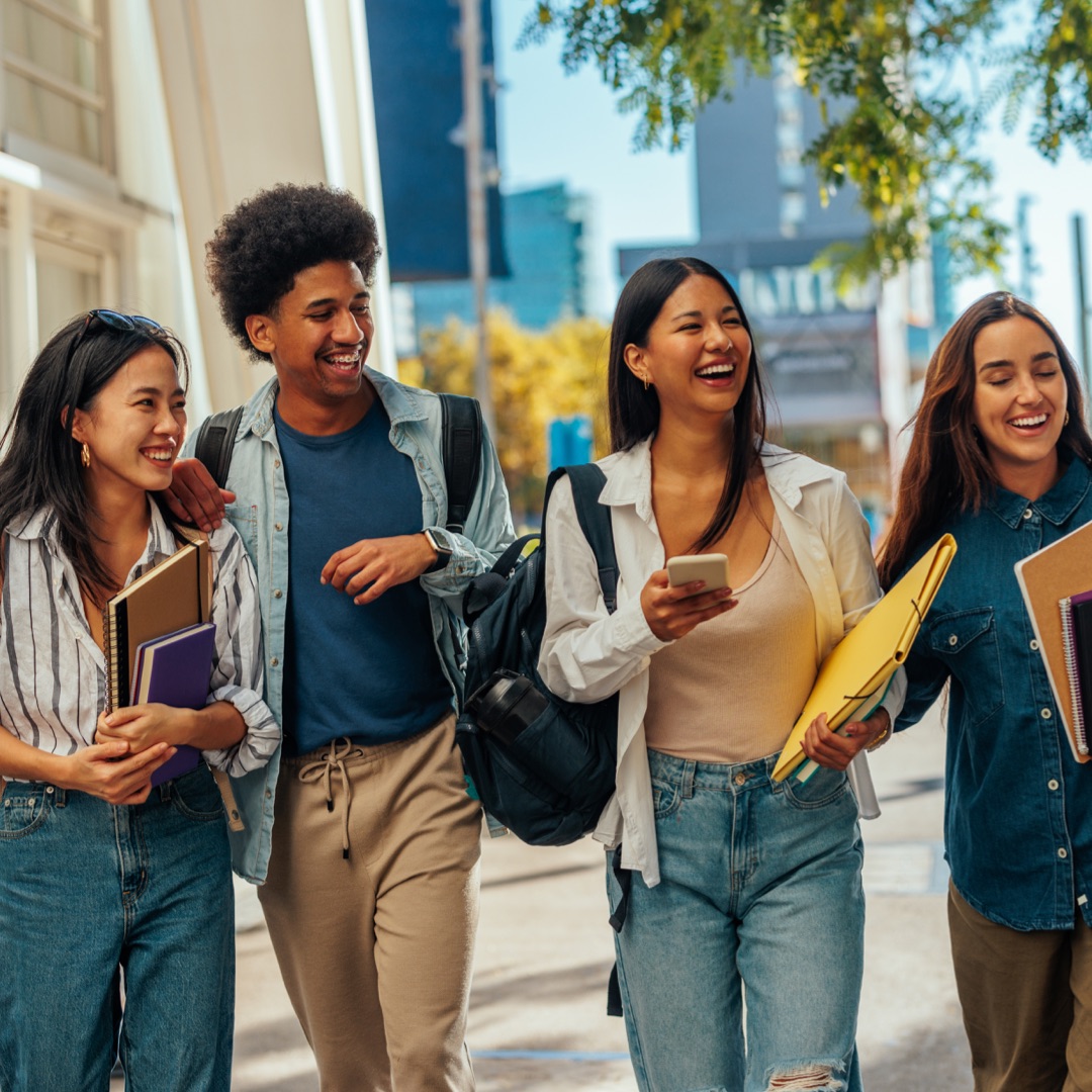A group in Australian international students laugh as they walk down a university corridor. 