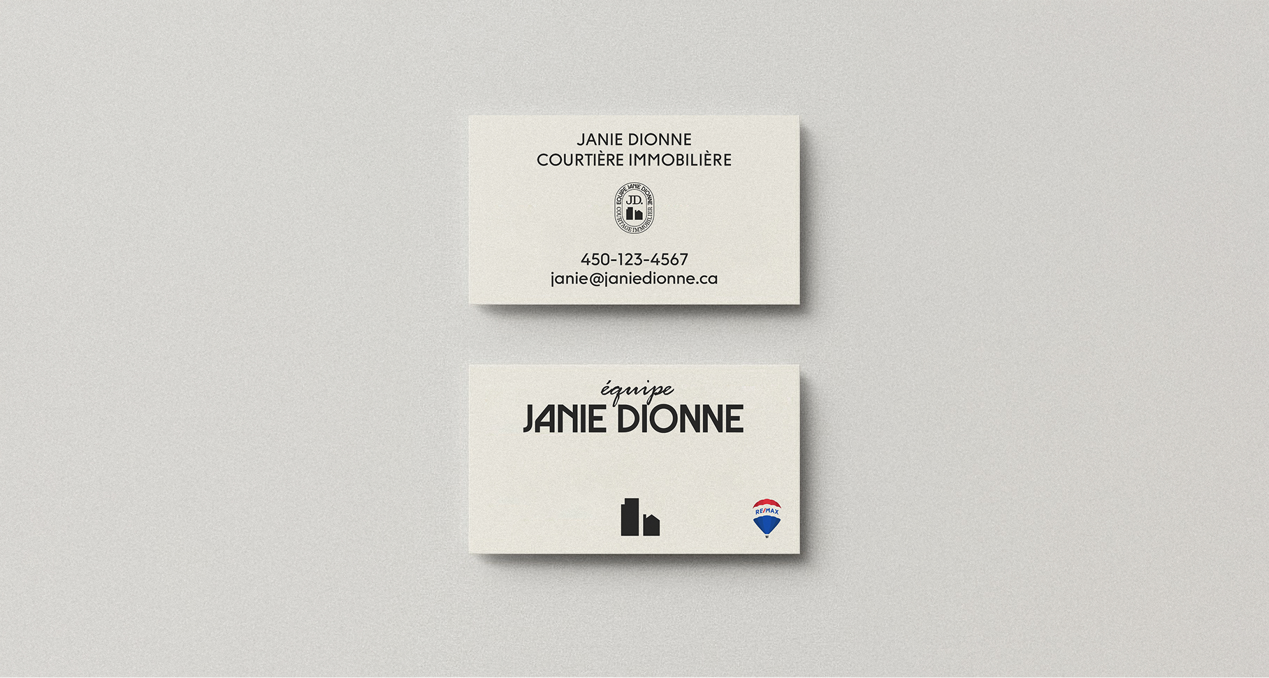 Deux cartes de visite pour l'Équipe Janie Dionne, courtière immobilière. La première affiche le nom, les coordonnées et un sceau professionnel. La seconde met en avant le logo de l'équipe avec une icône de bâtiments et le logo RE/MAX sur un fond beige texturé.