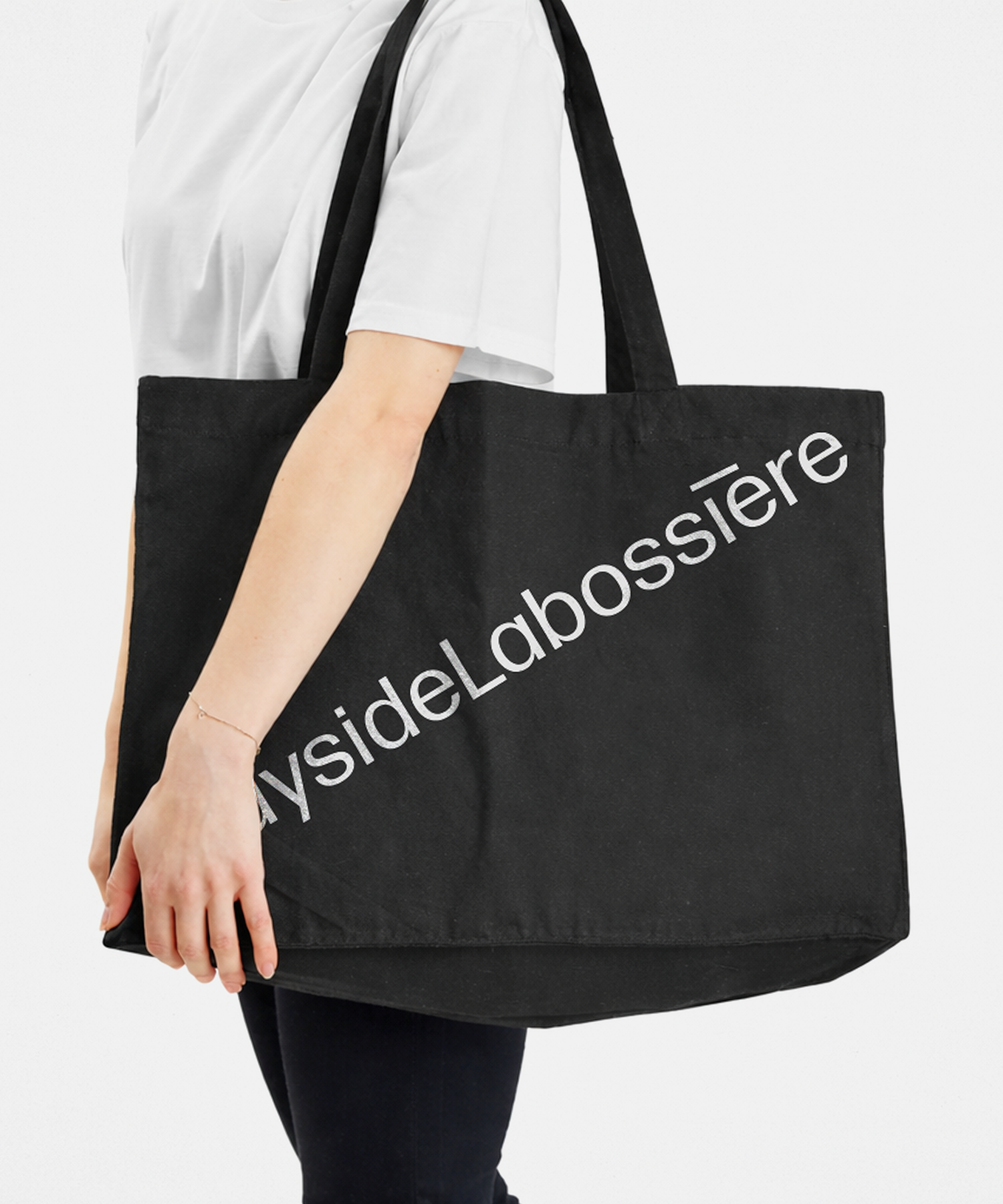 Sac fourre-tout noir en coton imaginé par l'agence Colosse comme objet promotionnel. Le logo Rayside Labossière y est imprimé en grand format et en diagonale argentée, créant un impact visuel fort et moderne.