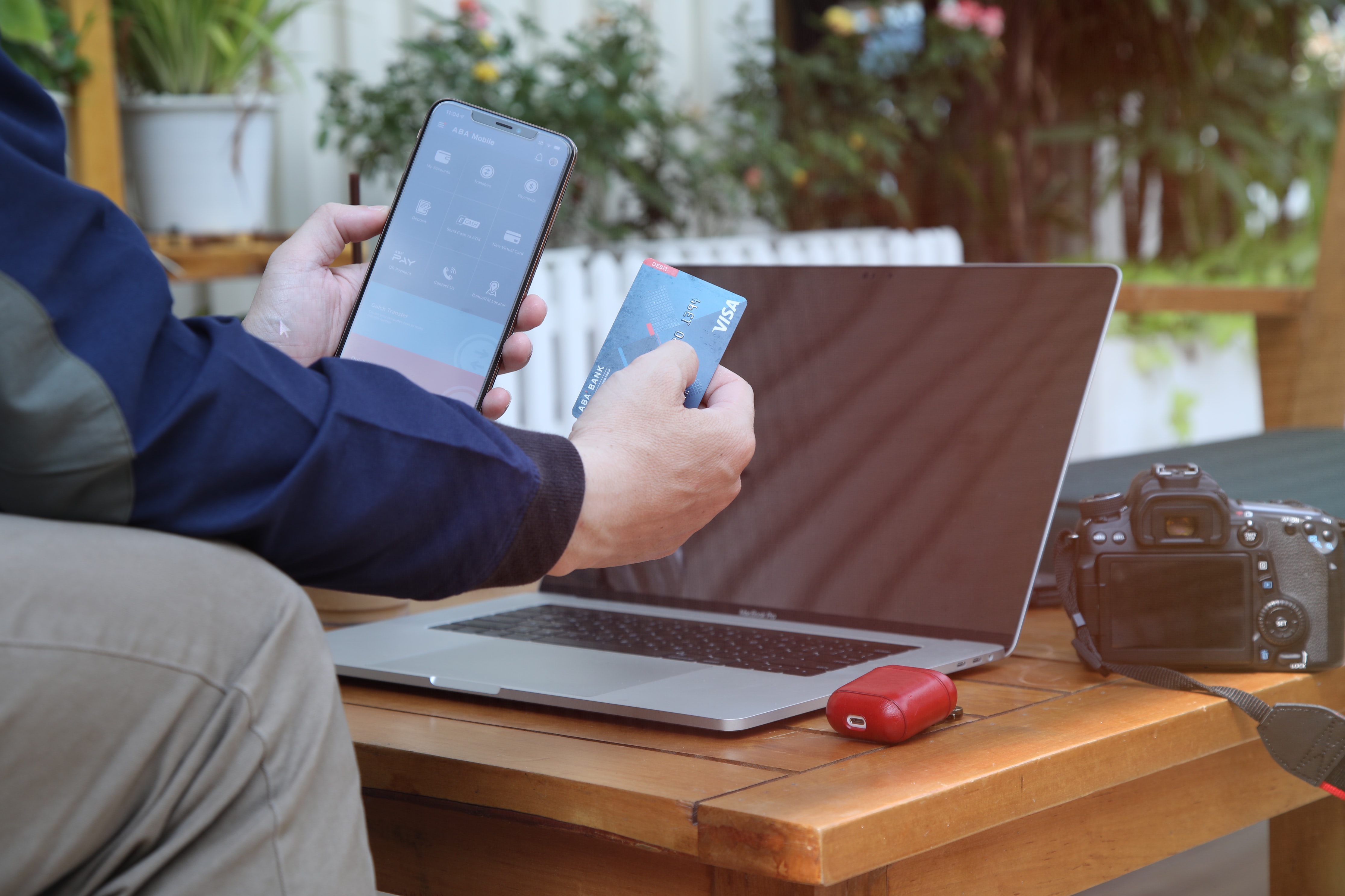 Man holding phone and credit card in front of laptop