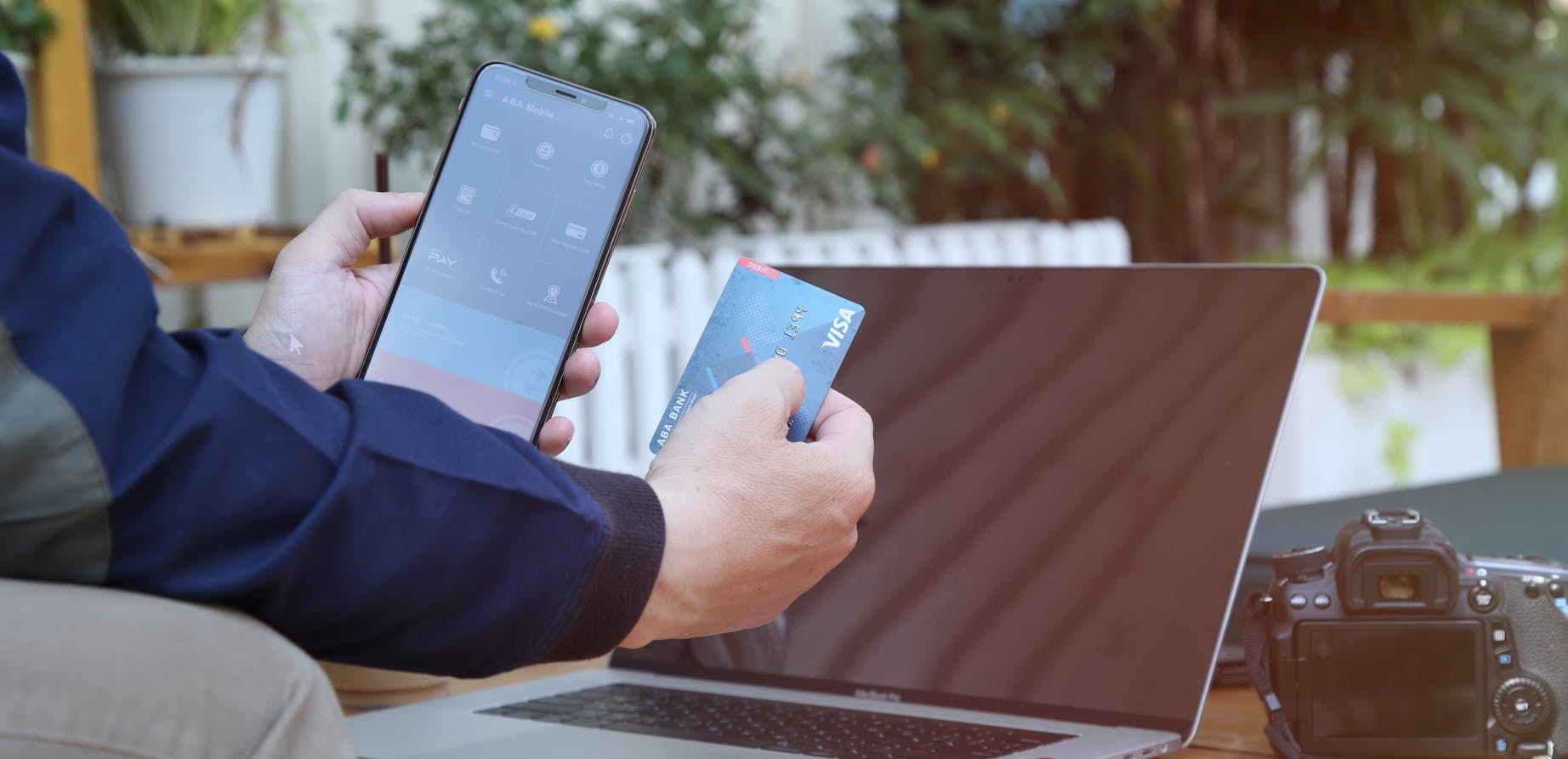 Man holding phone and credit card in front of laptop