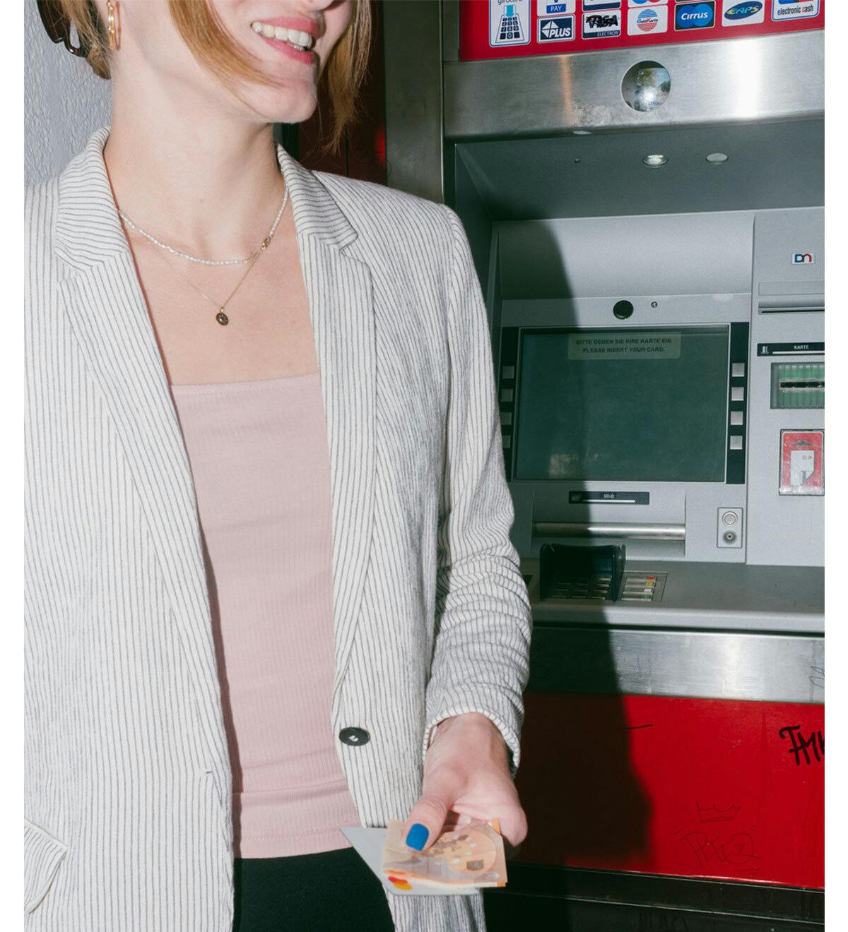 Una mujer sacando dinero del cajero automático.