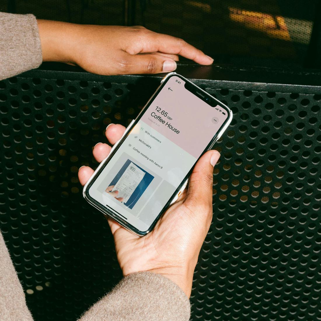 Employee holds a mobile phone with Pleo petty cash reimbursement app