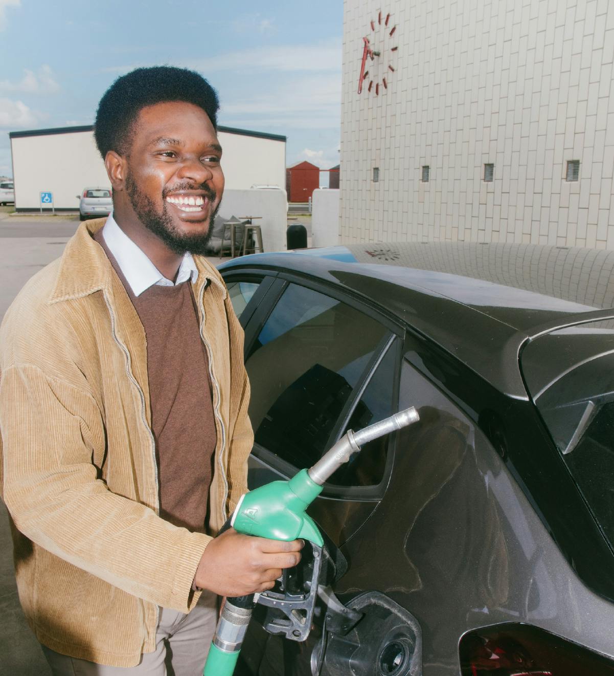 En glad ansatt som fyller bensin på bilen