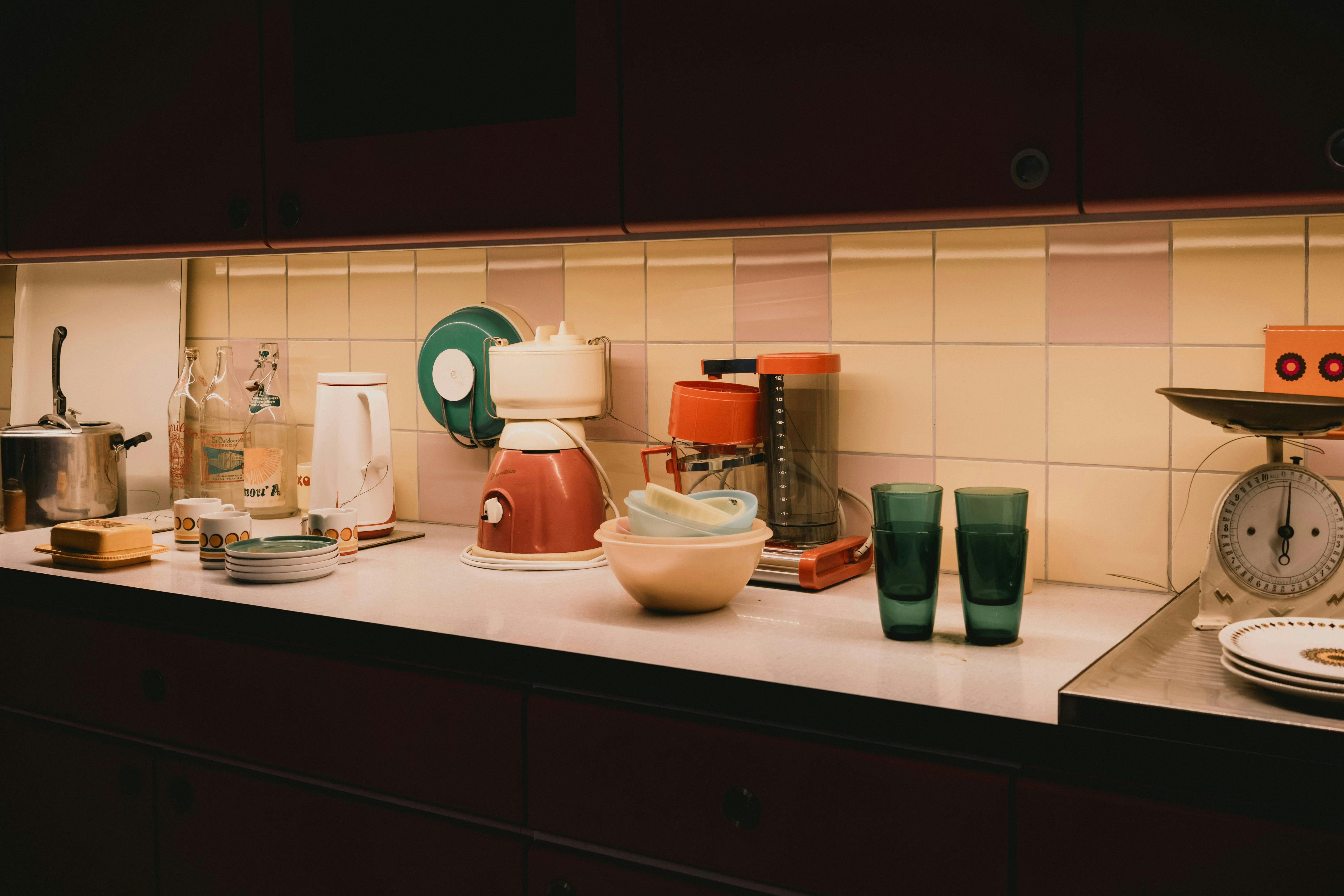 Photo d'un robot-cuiseur intelligent moderne sur un plan de travail de cuisine lumineuse, avec écran tactile allumé affichant une recette, entouré d'ingrédients frais et accessoires.