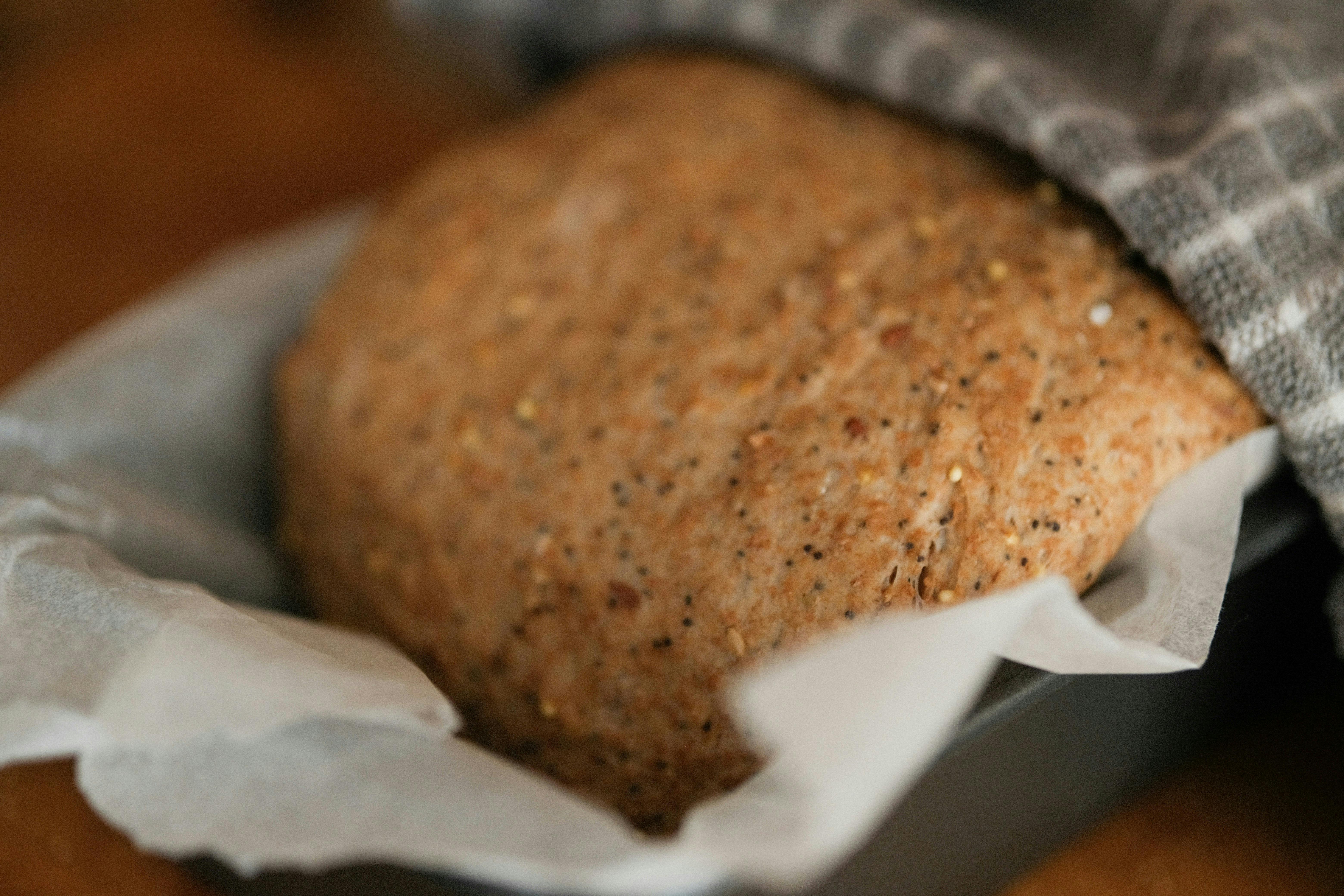 Photo d'une machine à pain moderne sur un plan de travail de cuisine, avec un pain fraîchement cuit à côté, ambiance chaleureuse et lumineuse.