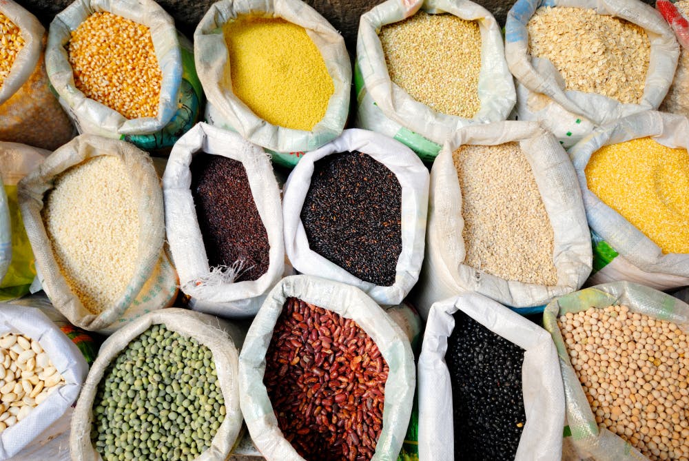 Open sacks of legumes and cereals such as  cowpea, soybeans, maize, and oat displayed at a market. 