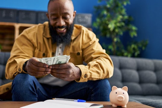 Man reviews his business records with a piggy bank holding the money he's saved