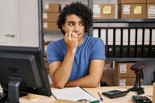 Small business owner sits at a desk looking nervous