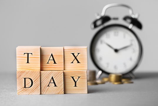 Blocks read "tax day" with a clock and coins in the background