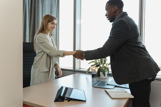 A business owner shakes hands with a businesswoman he's just hired