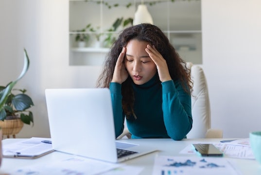 young businesswoman sits at her computer looking stressed and worried
