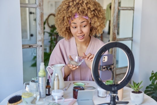 influencer gives a makeup tutorial while looking at her camera and ring light setup