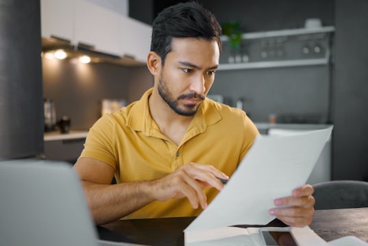 Small business owner sits in his home office and reviews a form