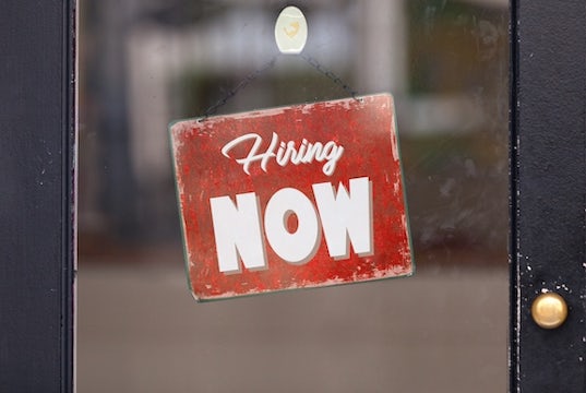 A help wanted sign hangs on a door