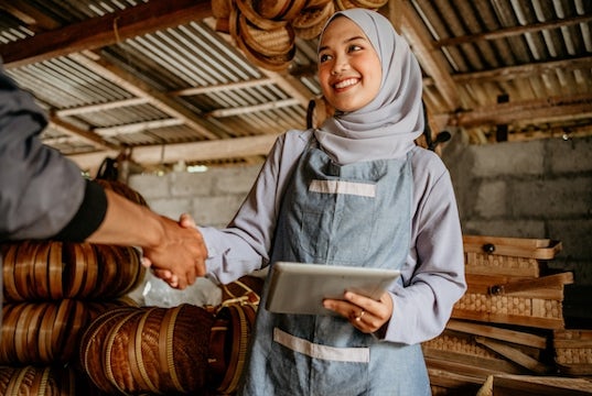 A young business owner at her warehouse shakes hands with an investor