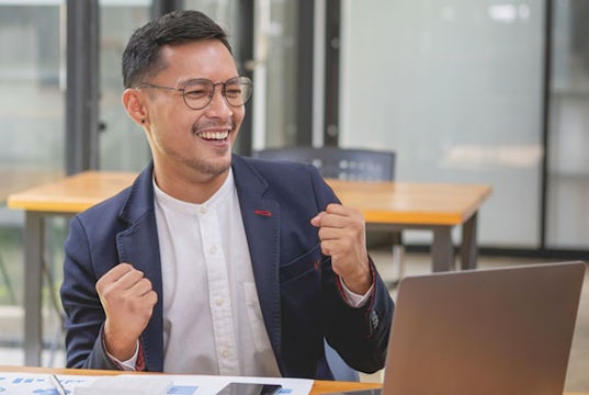 Young businessman excitedly reads his business's financial reports