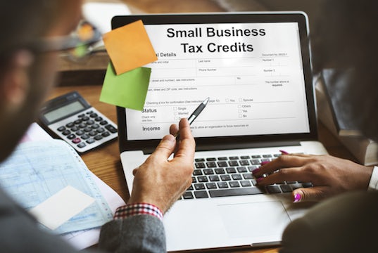 Colleagues view a laptop screen that displays a small business tax credit form
