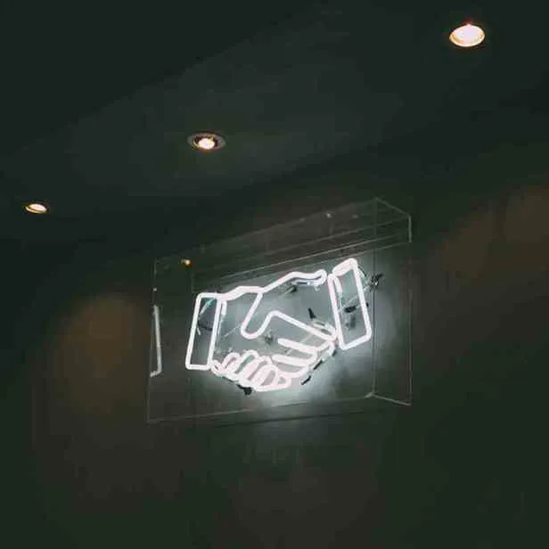 Neon sign of hands shaking