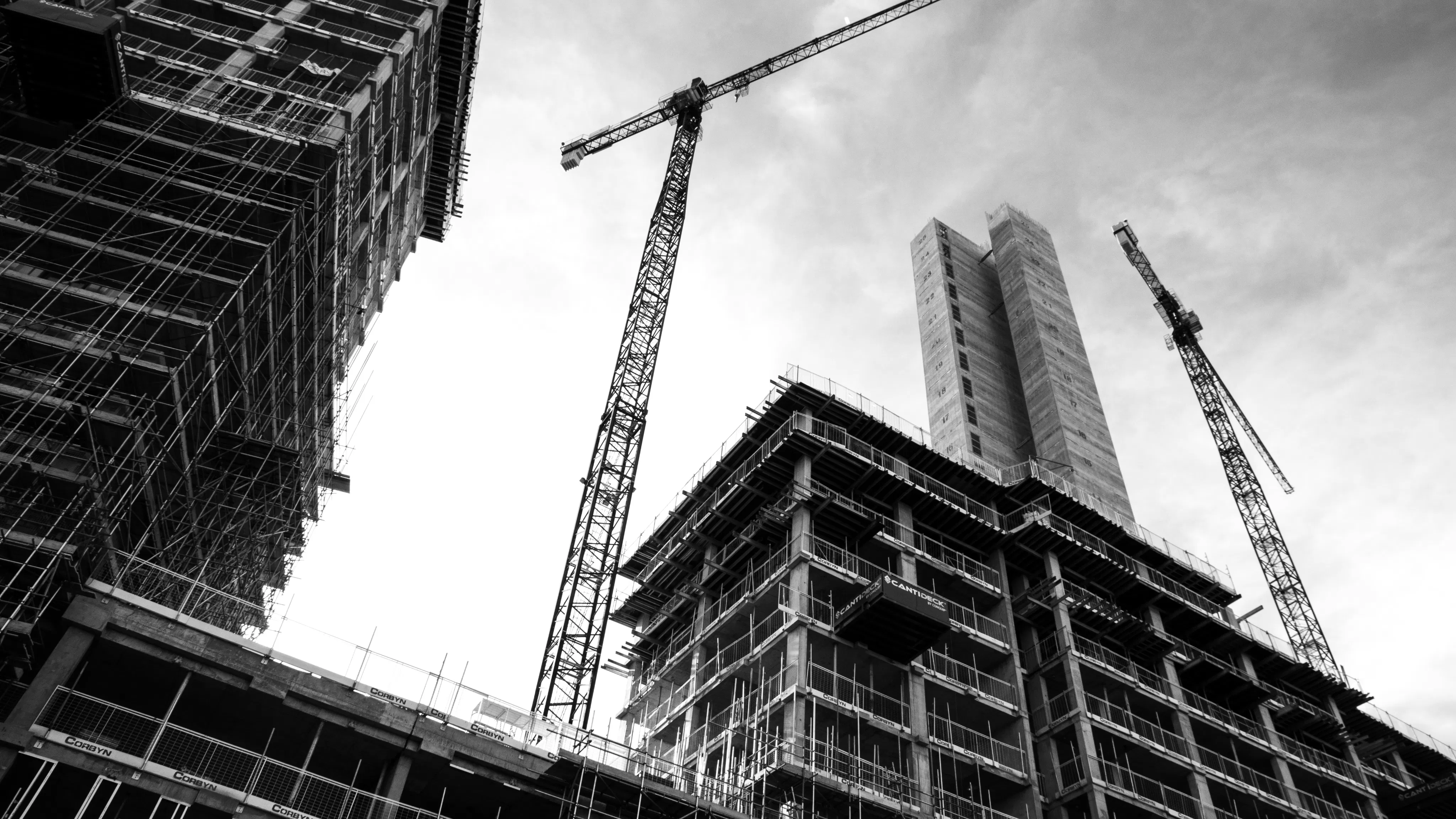 Bottom up view of crane over construction site in black and white