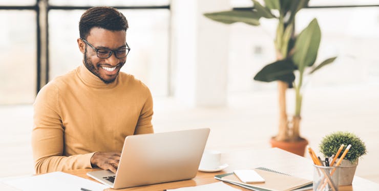 Homem sorrindo em frente ao computador