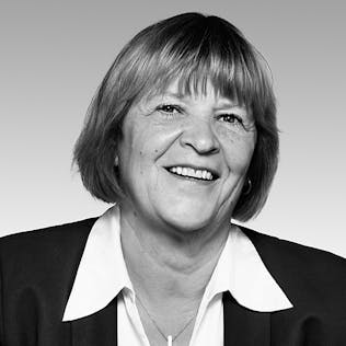 Eine lächelnde Frau mit weißer Bluse und schwarzer Jacke.