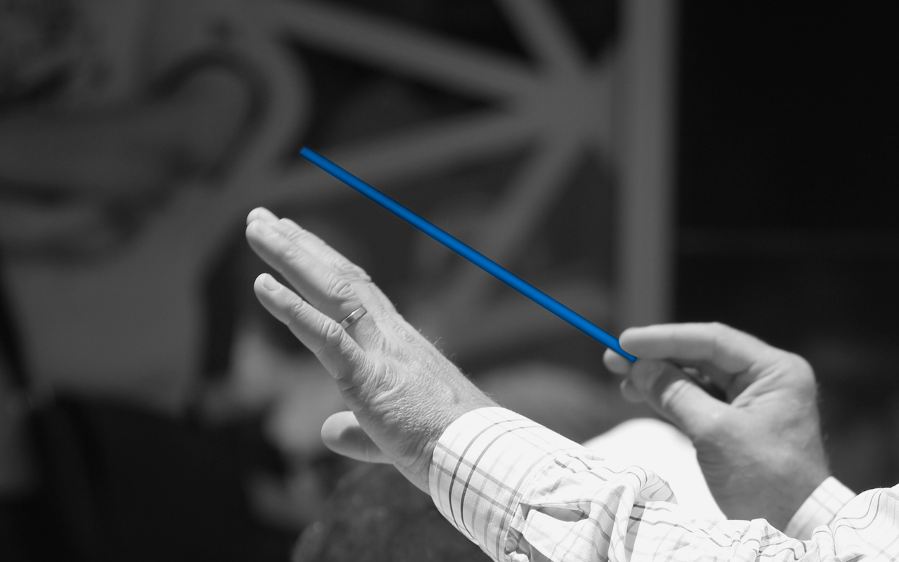 Zwei Hände und die rechte Hand hält einen Dirigentenstab. 