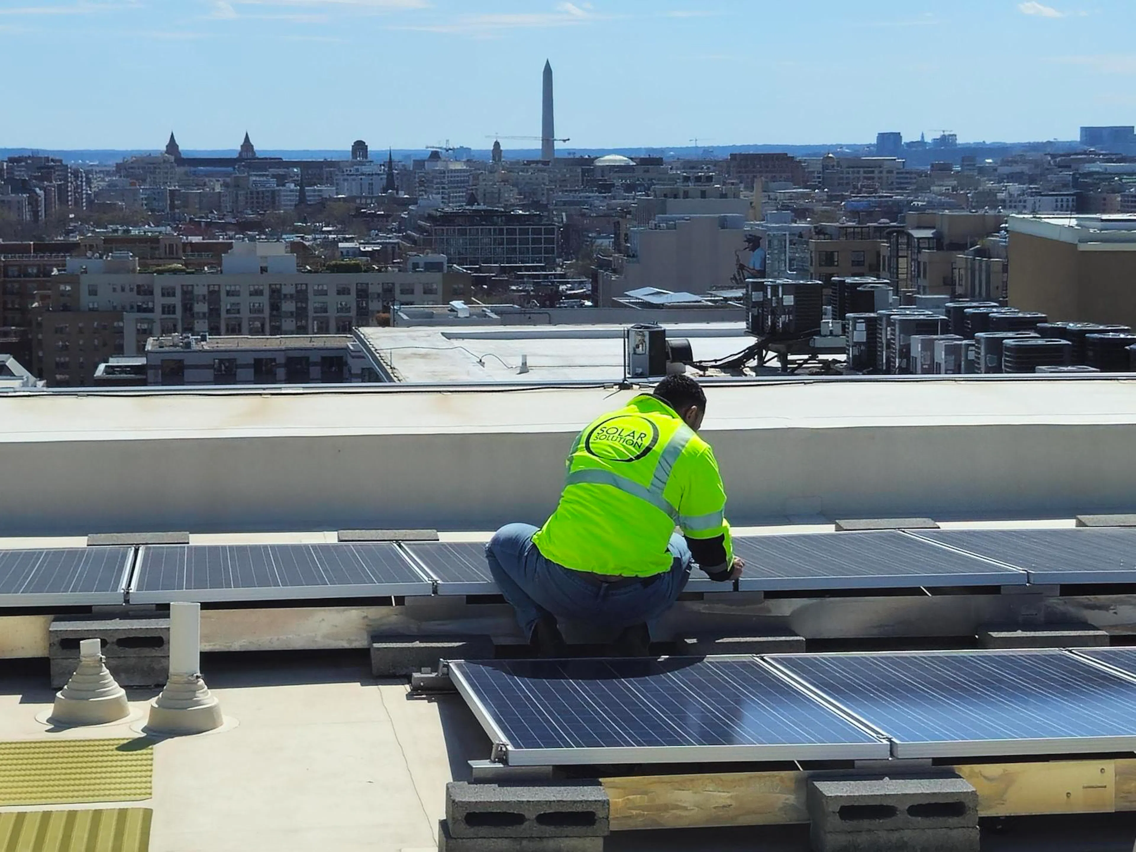 An installation crew member of Solar Solution putting rooftop solar panels on a downtown D.C. apartment building.