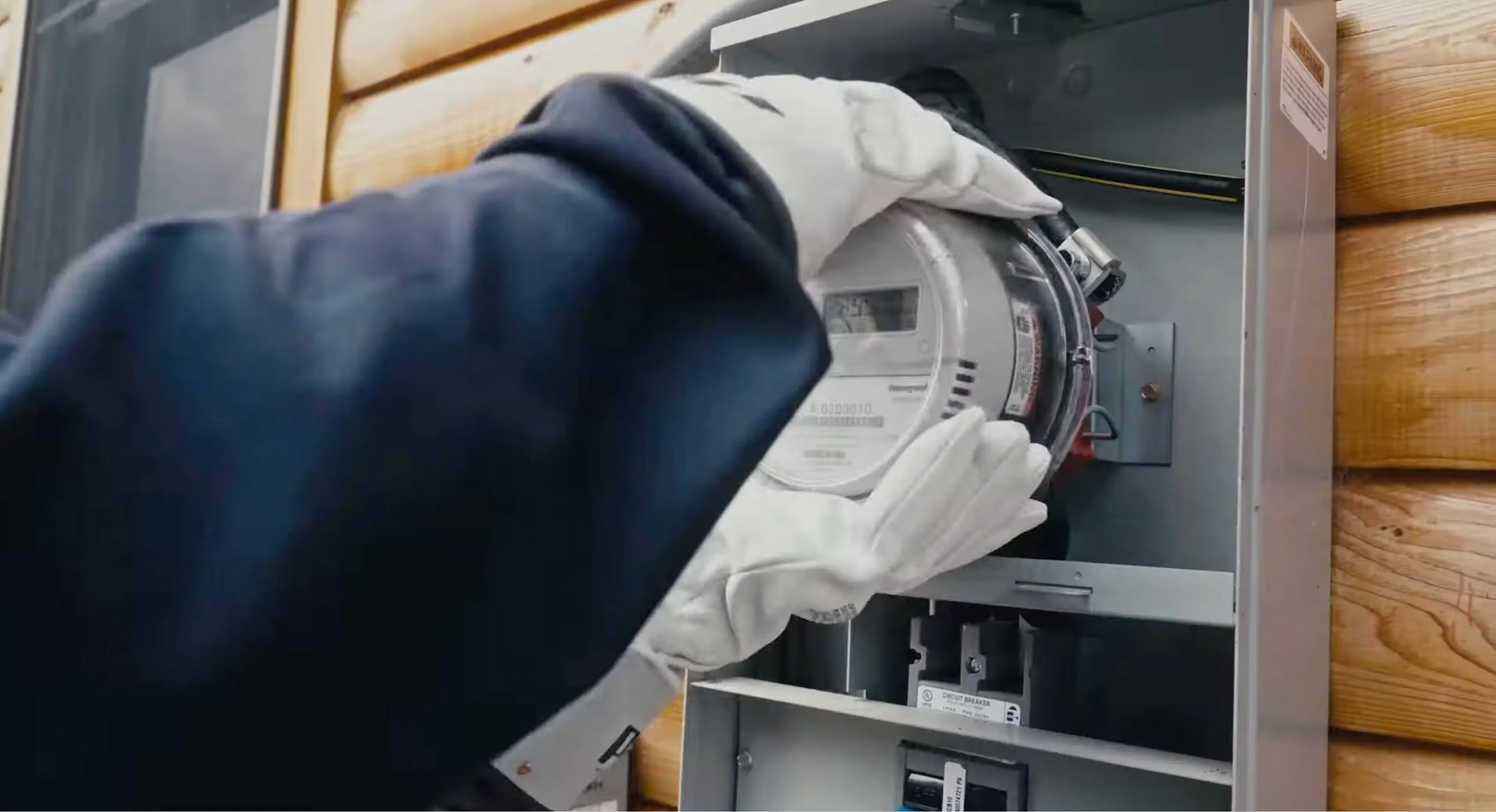 An electrician removing the utility billing meter from a home's meter socket box.