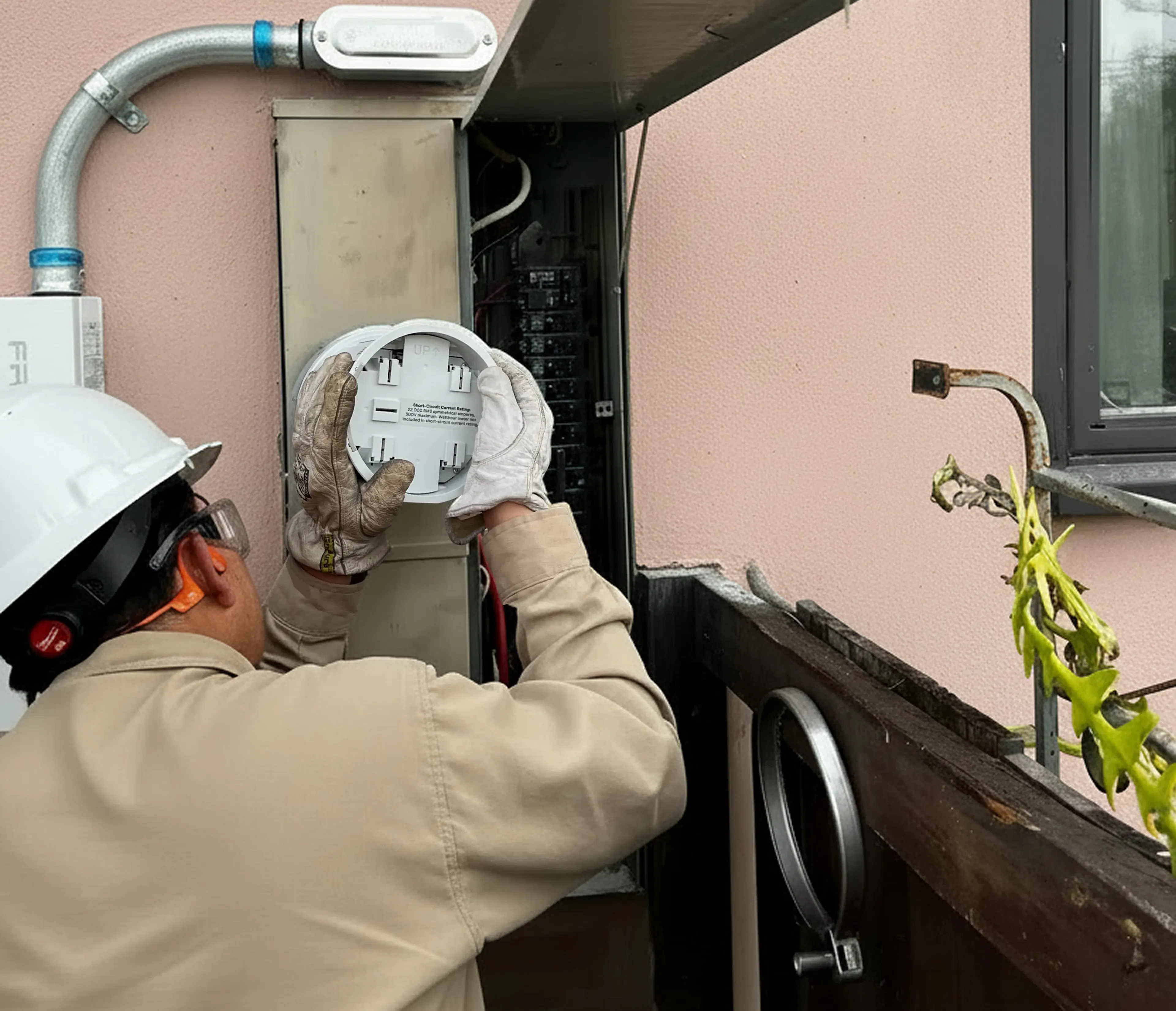 An electrician installs a meter collar into a meter-main-combo panel on the outside of a home.