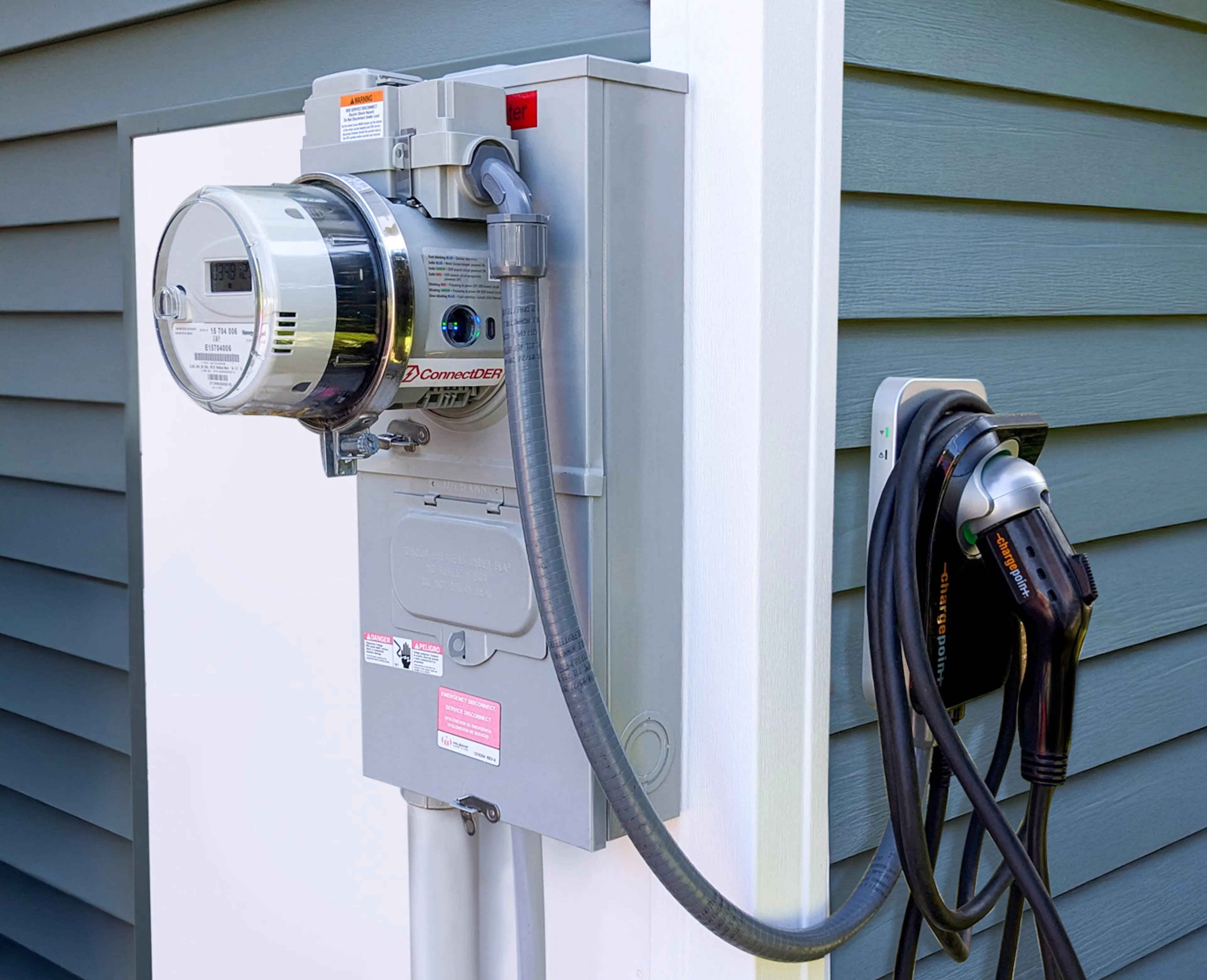 ConnectDER's EV Meter Socket Adapter installed in a home's meter can, with an EV charger plugged into it.