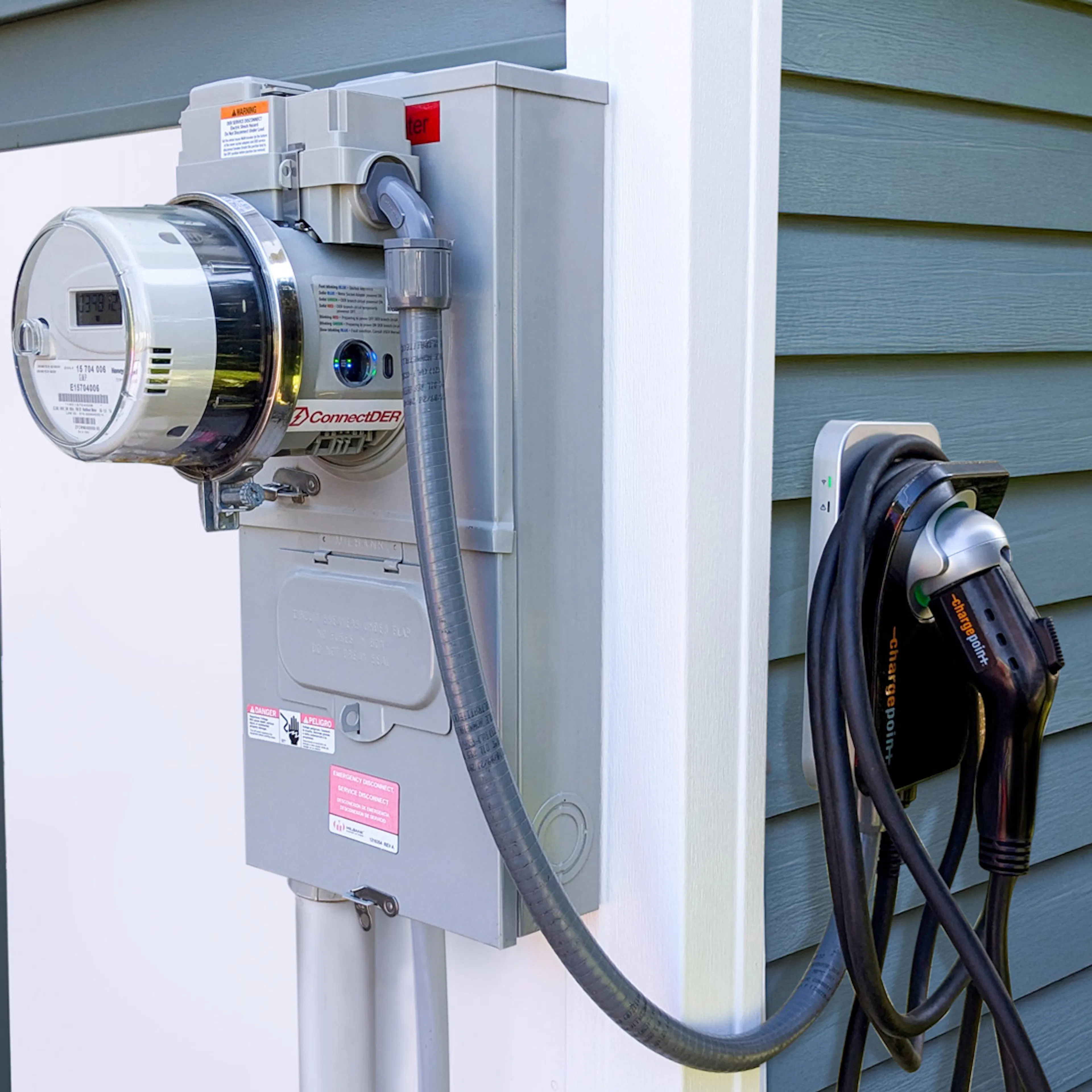 ConnectDER's EV Meter Socket Adapter installed in a home's meter can, with an EV charger plugged into it.