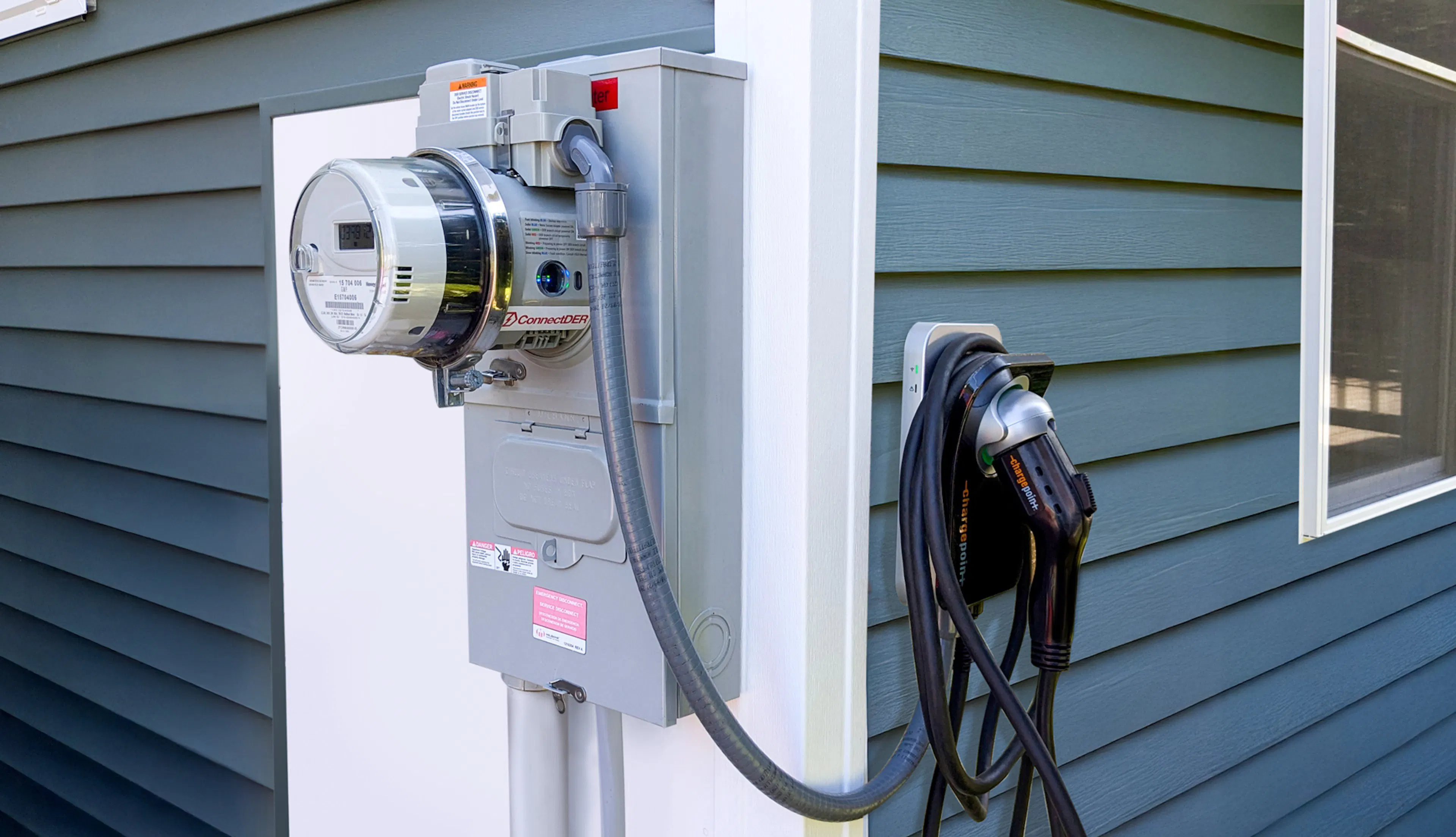 ConnectDER's EV Meter Socket Adapter installed in a home's meter can, with an EV charger plugged into it.