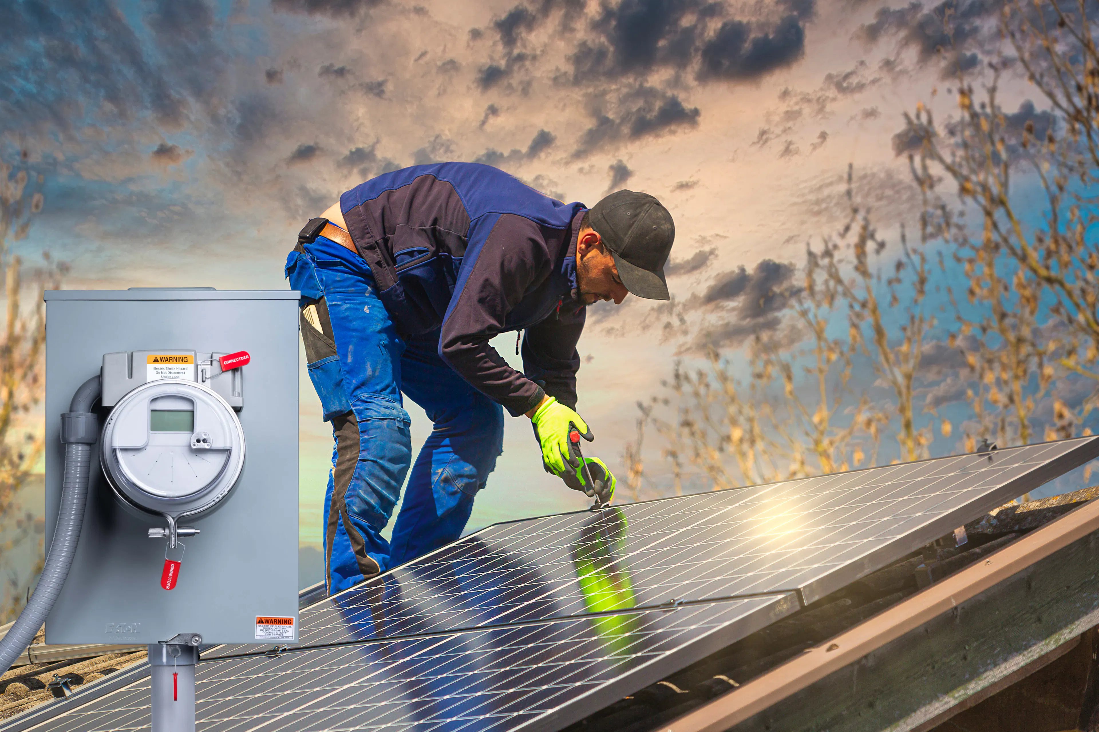 A rooftop solar installer stands on a roof as he mounts of large solar panel to the shingles.