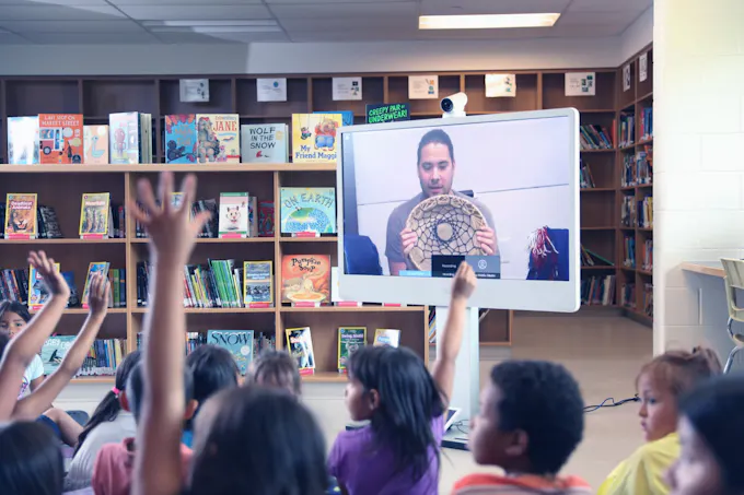Students watching a live virtual learning session in their classroom.