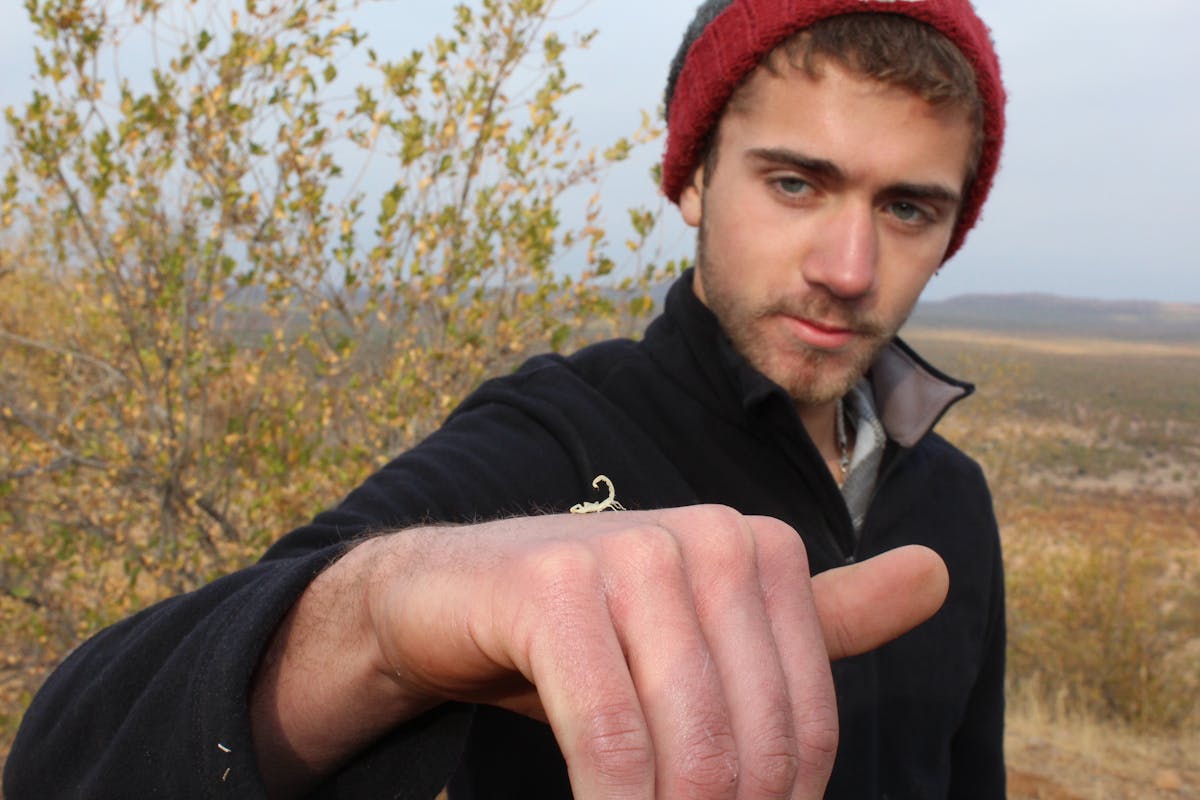 Close-up of a male posing with a scorpion on his hand