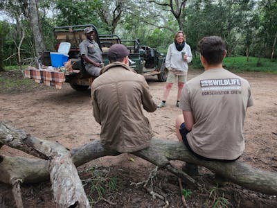 Phinda Wildlife Research Project: group of volunteers relaxing by the vehicle with a guide