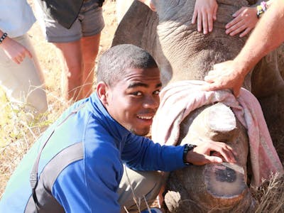 A group of ACE school students posing with a sedated rhino