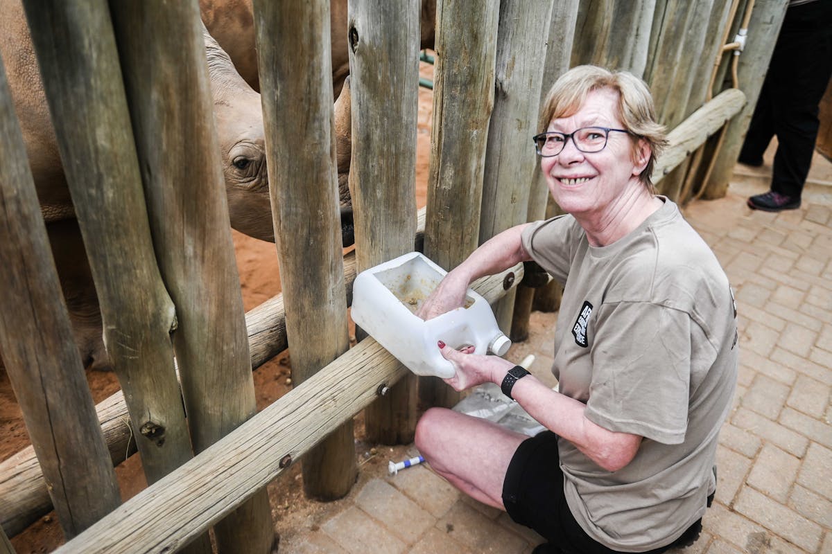 Norma Falconer: smiling at the camera while feeding the rhinos at Care for Wild Africa