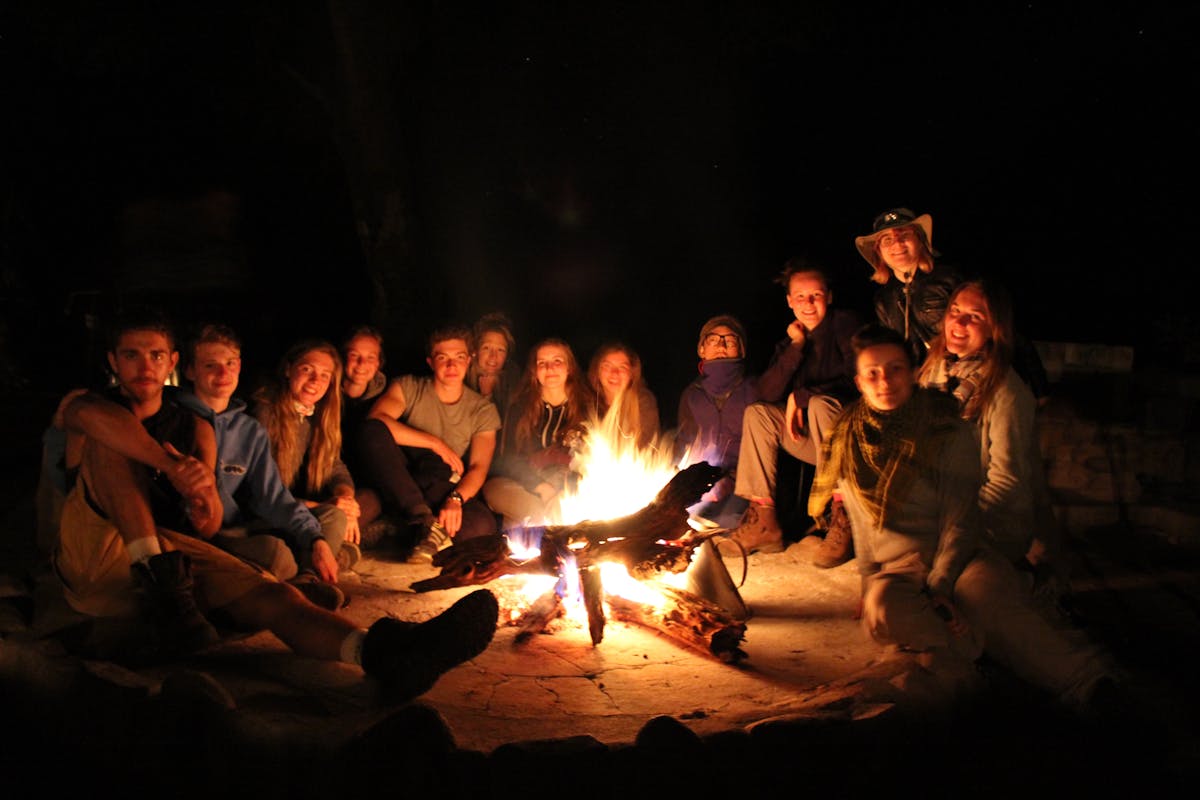 Group of students relaxing around a campfire